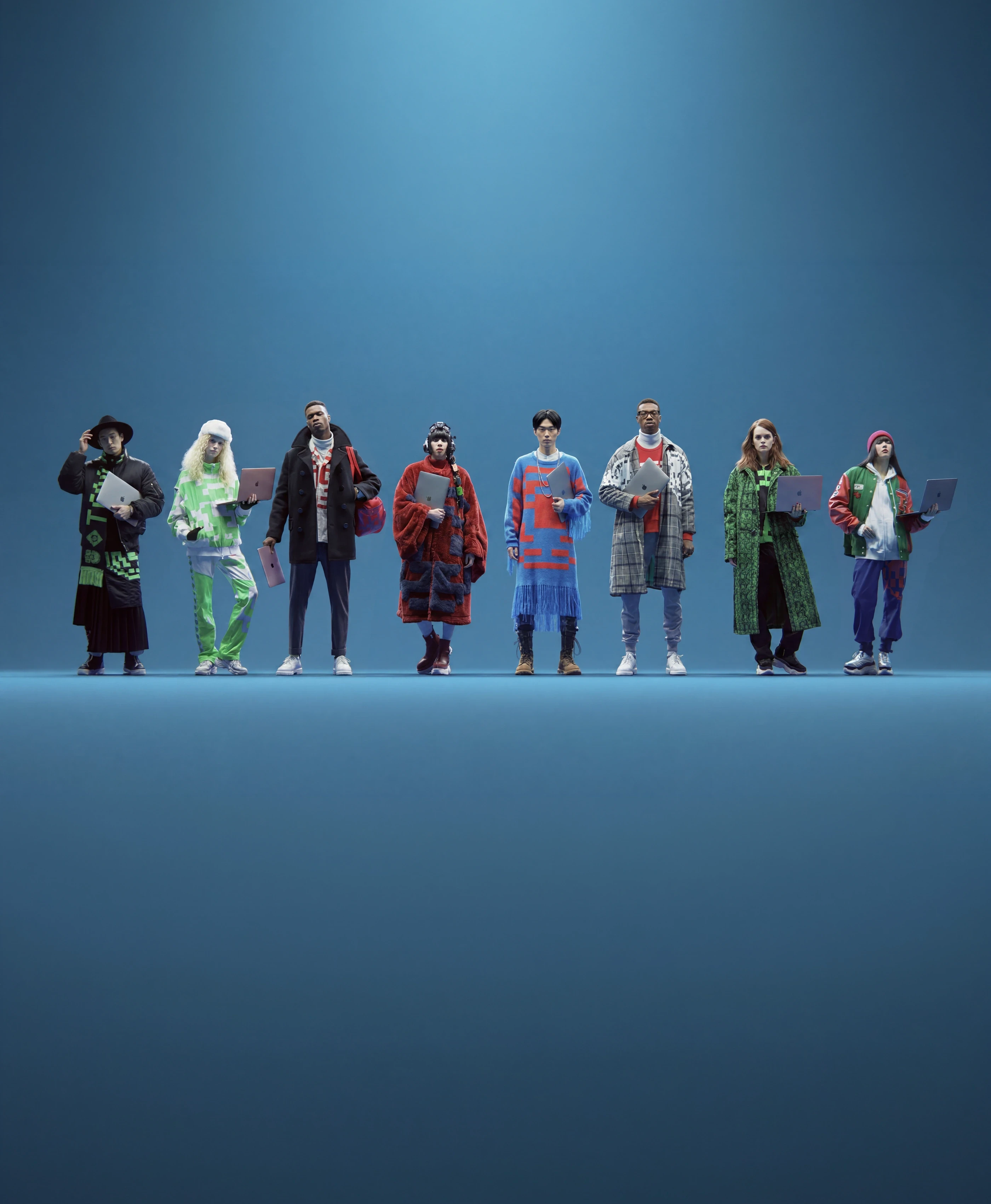 Eight product-team members standing in a row, each holding a laptop, on a blue studio background